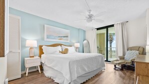 A bedroom with a bed, nightstands, a chair, and a view of the outdoors. - Direct Oceanfront! Renovated! All beach gear included (North Myrtle Beach)
