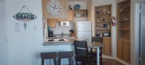 Une cuisine compacte équipée d’un four à micro-ondes, d’un réfrigérateur et d’un petit coin repas avec deux chaises.