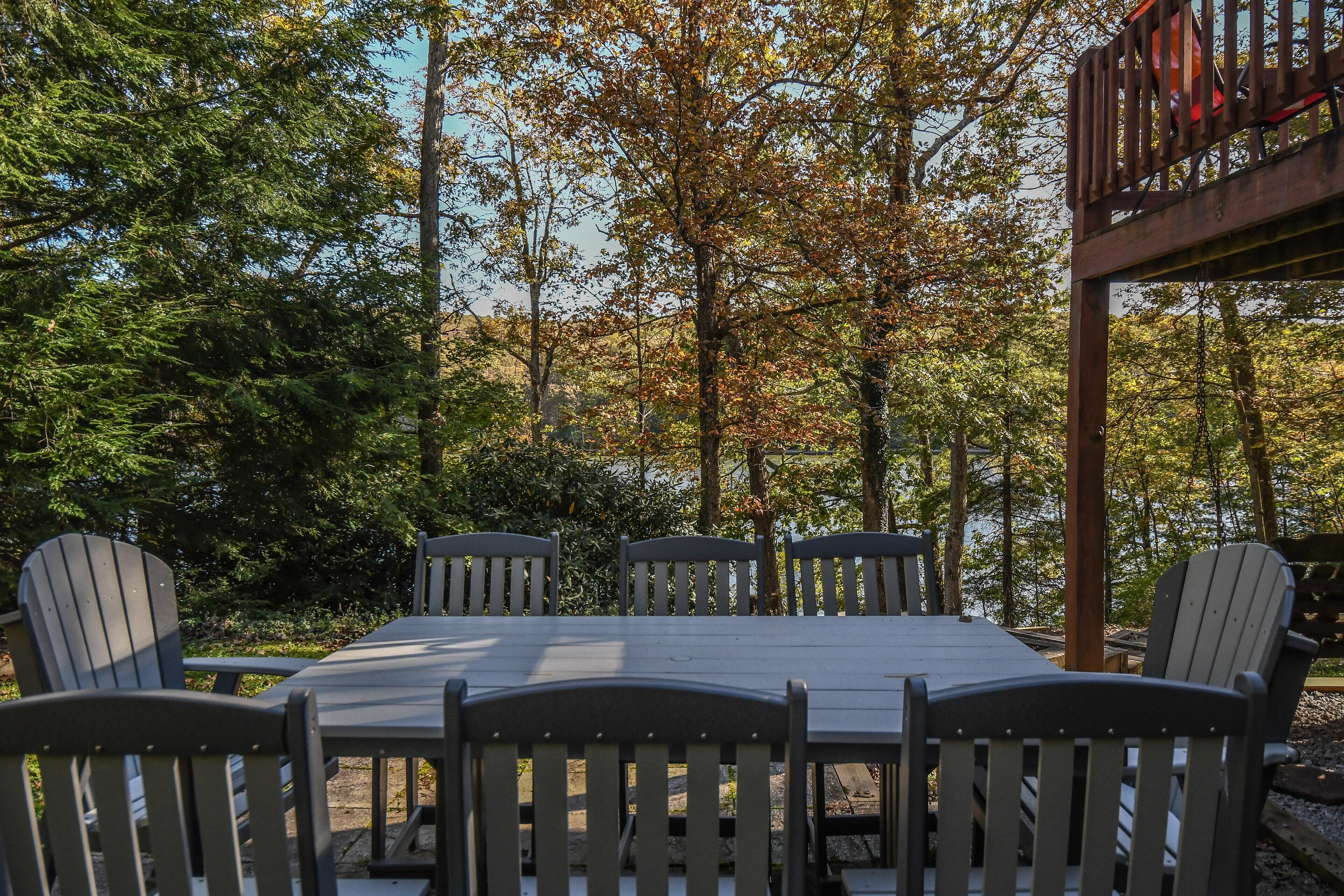 A wooden deck with a table and chairs, surrounded by trees.