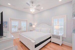 A bedroom with a bed, nightstands, a ceiling fan, and windows. - Sanctuary at Navarre Beach - 8 BR/8 BA Beach House w/pool. (Navarre Beach)