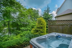 Relax in a serene hot tub surrounded by lush greenery and a deck.