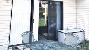 Ein zweistöckiges Gebäude mit Balkon, einer Schiebetür aus Glas und einer Terrassenfläche mit Tisch und Stühlen.