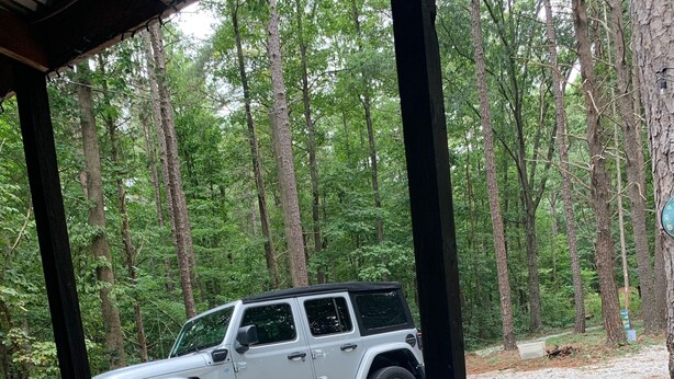 A white Jeep parked on a gravel path in a wooded area. - The Cozy Cottage (Toccoa)