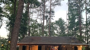 A rustic cabin with a wooden deck, two chairs, and a small table. - The Cozy Cottage (Toccoa)