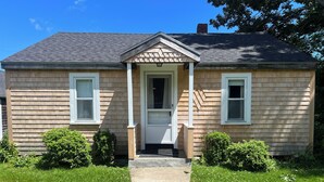 A two-story house with a front porch, a central door, and two windows on the first floor.