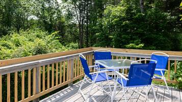 Une terrasse en bois avec une table en verre et des chaises bleues.