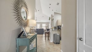A modern kitchen with a coffee maker, a trash bin, and a dining area with a table and chairs.