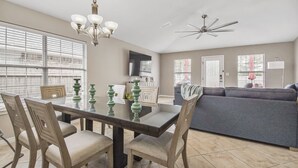 A modern living room with a dining area, a grey sofa, and a chandelier.
