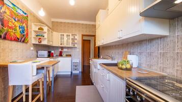 A modern kitchen with white cabinets, a wooden countertop, and a stainless steel stove.
