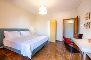 Una habitación de hotel con cama, escritorio, laptop, silla y espejo.