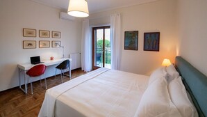 A hotel room with a bed, a desk with a laptop, a chair, and a window with curtains.