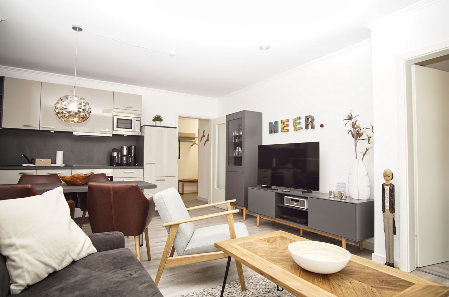 A modern living room with a grey sofa, a wooden coffee table, and a TV.