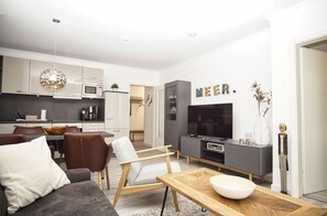 Una sala moderna con un sofá gris, una mesa de centro de madera y un televisor.