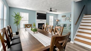 Un comedor con mesa de madera, sillas y ventilador de techo.
