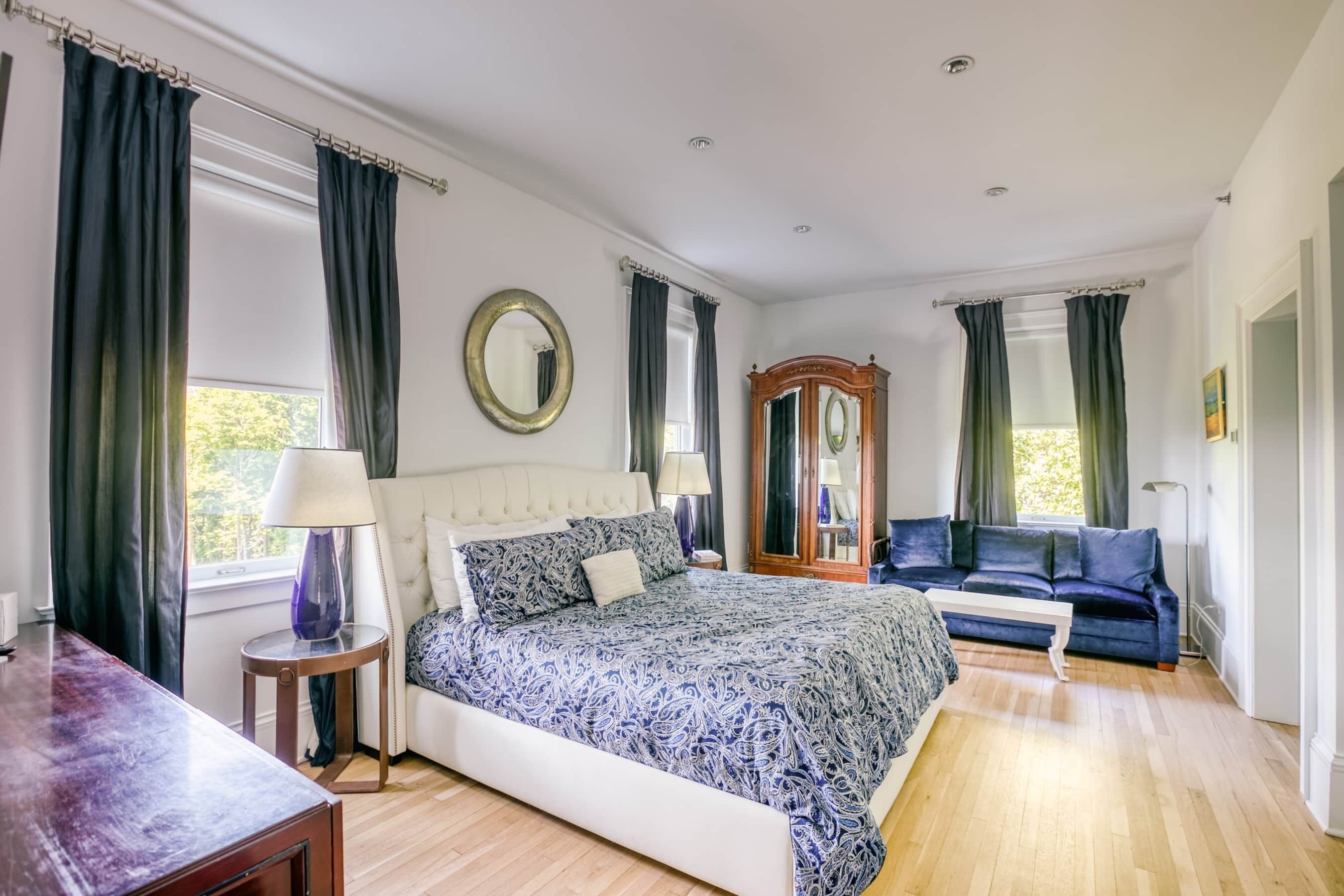 Une chambre à coucher avec un grand lit, un canapé, une armoire en bois et un miroir.