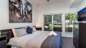 Een moderne hotelkamer met een groot bed, een televisie, een bureau en een raam met uitzicht op het omliggende landschap.