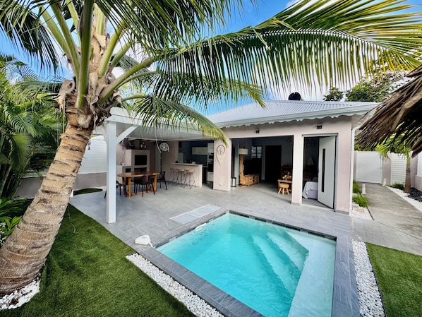 Une maison moderne dotée d’une piscine, d’un espace salon extérieur et d’un patio couvert.