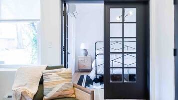 A modern bedroom with a bed, a nightstand, a lamp, and a window.