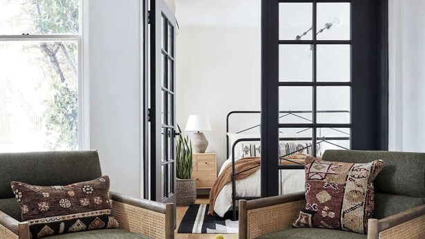 Una sala de estar moderna con dos sofás verdes, una mesa de centro redonda con un jarrón de flores amarillas y una alfombra de diseño blanco y negro.