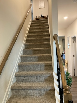 Staircase leads to an upper floor with a framed sign above.
