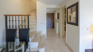 A staircase leading to a second floor, a dining area with a glass table and chairs, and a kitchen area in the background. - VILLA RIVIERA - Luxury villa with private pool in a fabulous urbanization on the Costa del (Mijas)