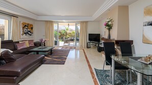 A modern living room with a leather sofa, glass coffee table, and a dining area with a glass table and chairs. - VILLA RIVIERA - Luxury villa with private pool in a fabulous urbanization on the Costa del (Mijas)