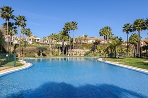 A large, clear swimming pool surrounded by palm trees and a well-maintained lawn. - VILLA RIVIERA - Luxury villa with private pool in a fabulous urbanization on the Costa del (Mijas)