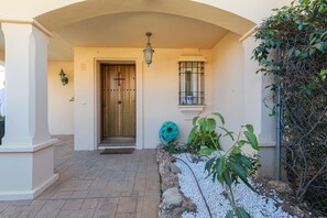 A building entrance with a tiled patio, a wooden door, a lantern, and a window with a metal grille. - VILLA RIVIERA - Luxury villa with private pool in a fabulous urbanization on the Costa del (Mijas)