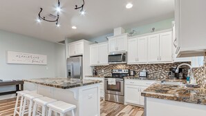 A modern kitchen with white cabinets, a granite countertop, and a built-in oven. - Amazing Outdoor Space, Beautiful Interior with King Beds, Easy Walk to Beach! (Crystal Beach)