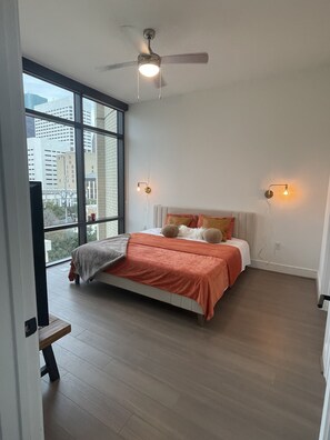 Enjoy a city view from the large window in this stylish bedroom featuring a comfortable bed and modern decor.