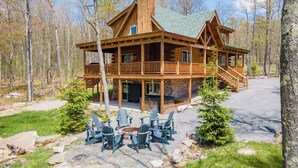 Eine Holzhütte mit einer Veranda, Sitzgelegenheiten im Freien und einer Feuerstelle.
