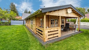Eine Holzhütte mit Veranda, Satellitenschüssel und einer kleinen Sitzgelegenheit im Freien.