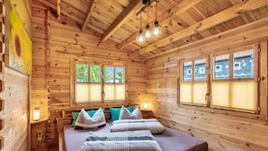 Ein Schlafzimmer einer Holzhütte mit Bett, Kissen, einem Nachttisch und einem Bild.