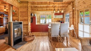Ein Holzblockhaus-Interieur mit Essbereich, Küche und Kamin.