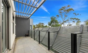 Enjoy the serene atmosphere of this outdoor space with a metal railing design, light-colored tiles, and a cozy bench.