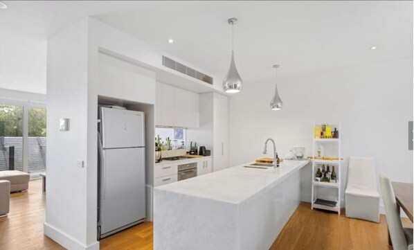 Enjoy cooking in this well-lit kitchen with a large island, refrigerator, and ample counter space.