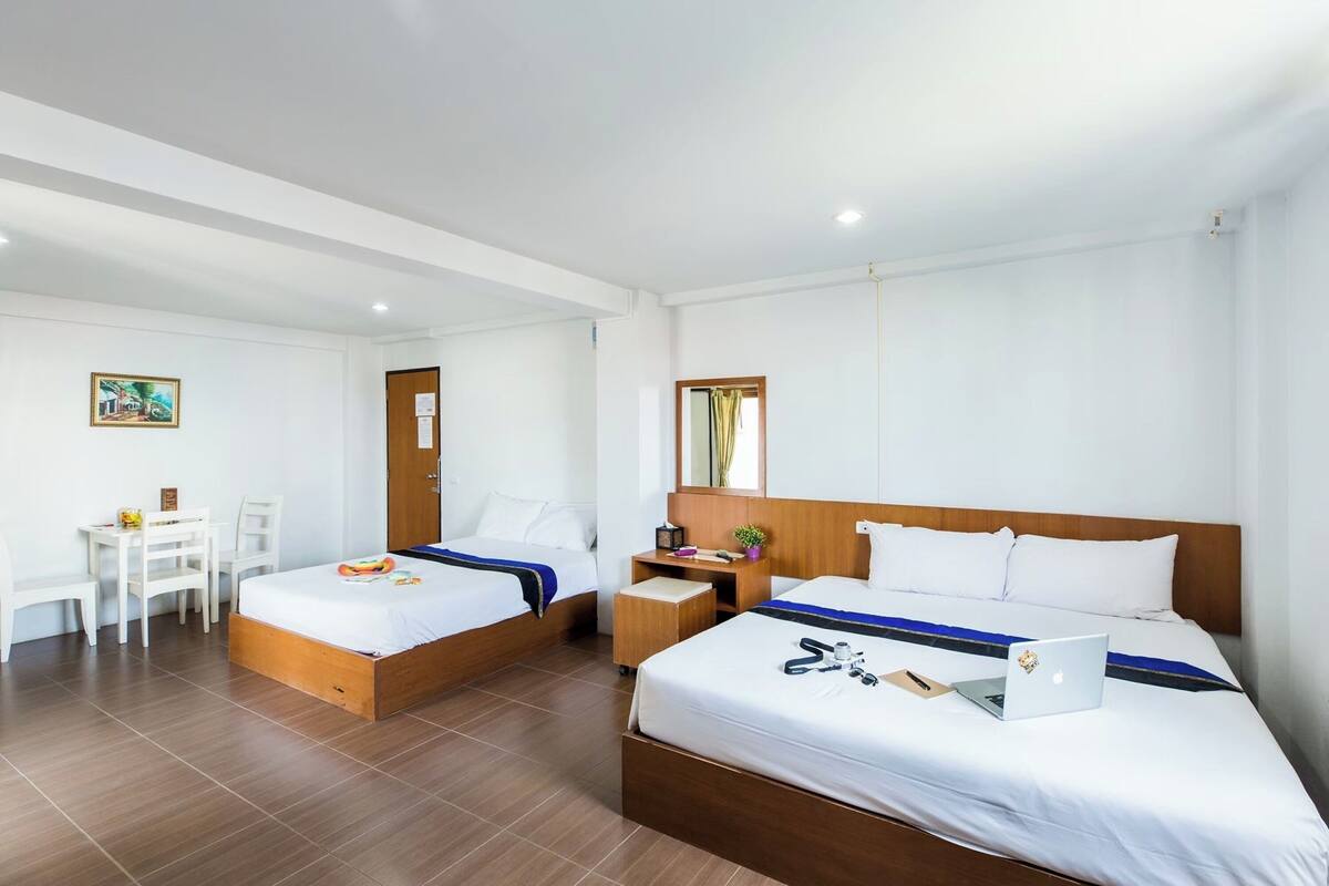 Een hotelkamer met twee enkele bedden, een bureau, een stoel en een klein tafeltje.