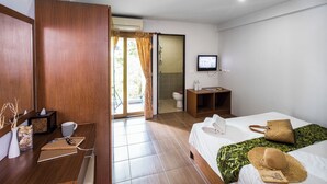 A hotel room with a bed, a desk, a television, and a bathroom visible through an open door.