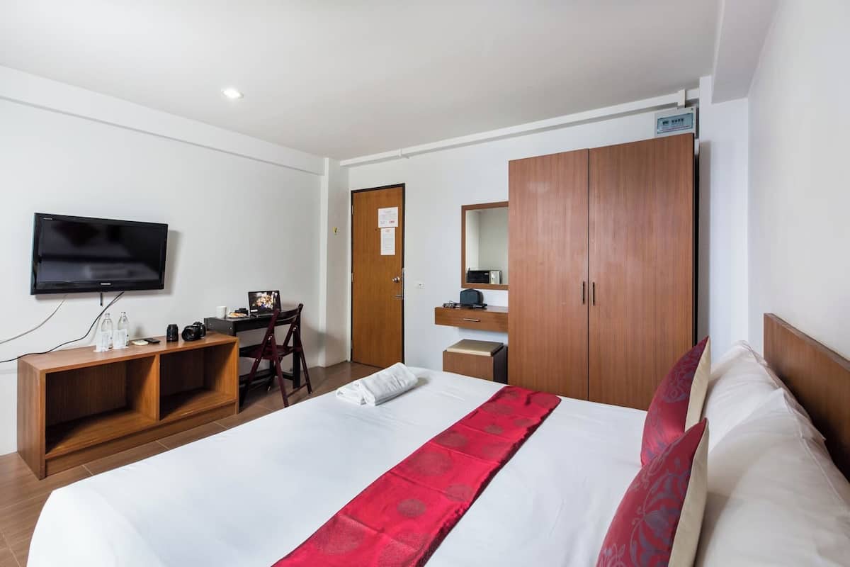 Een hotelkamer met een bed, bureau, televisie en kledingkast.