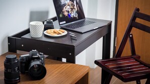 A workspace with a laptop, camera, mug, and plate of cookies on a wooden desk.