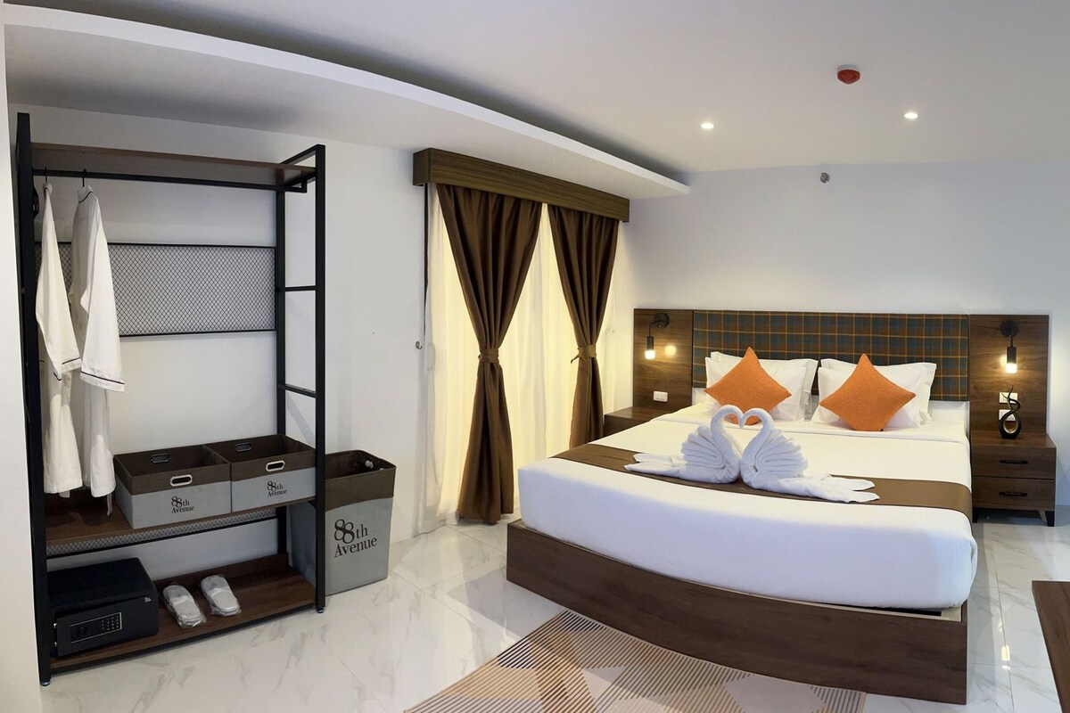 A hotel room with a bed, a wardrobe, a nightstand, and a bathroom area.