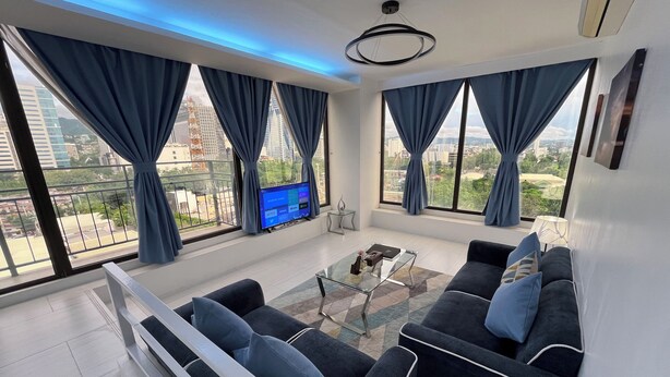 A modern living room with a sofa set, a coffee table, and a TV displaying a streaming service interface. - 88th Avenue (Cebu City)