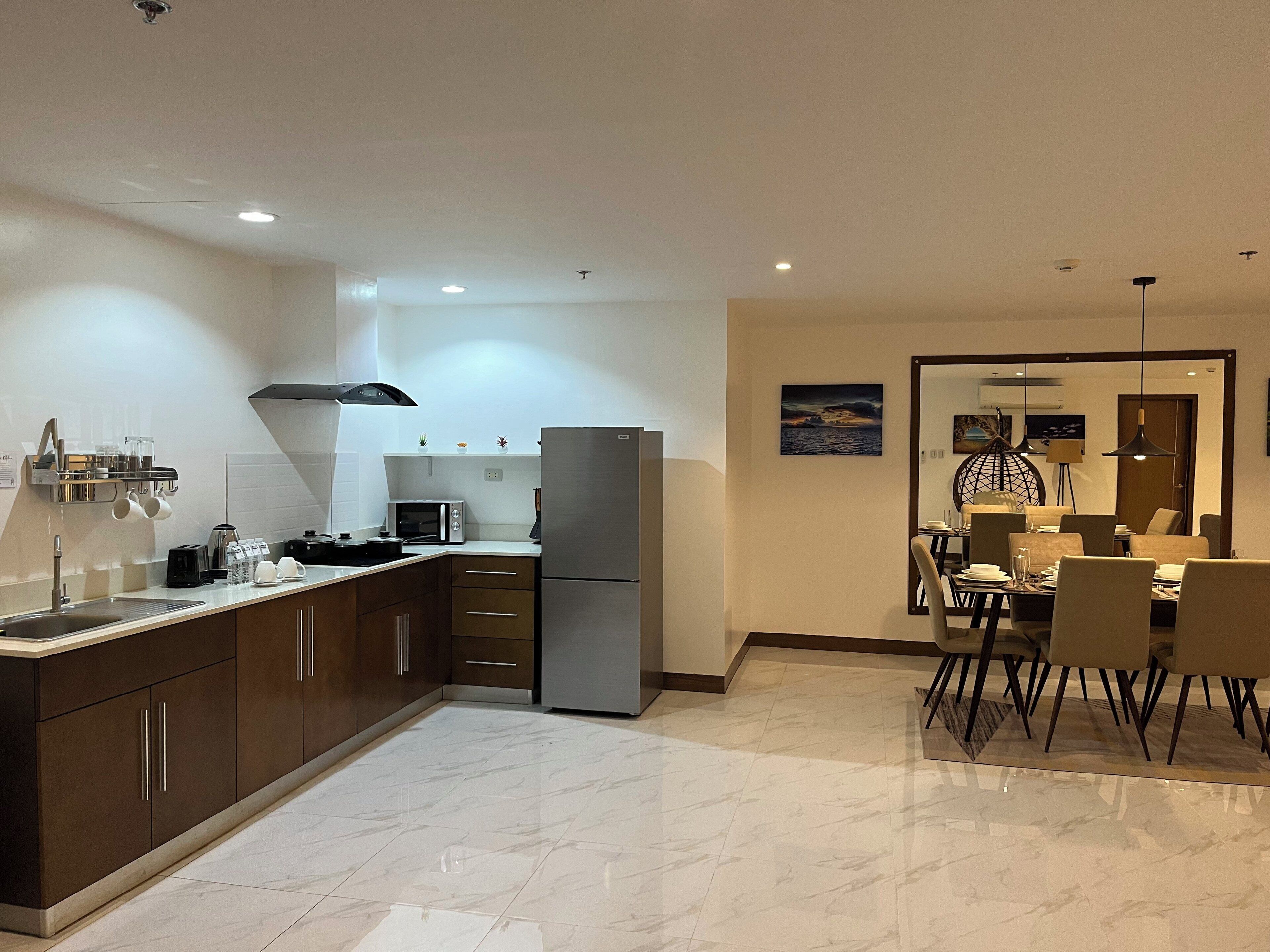 A modern kitchen with a built-in oven, microwave, and refrigerator. There is a dining area with a table and chairs.