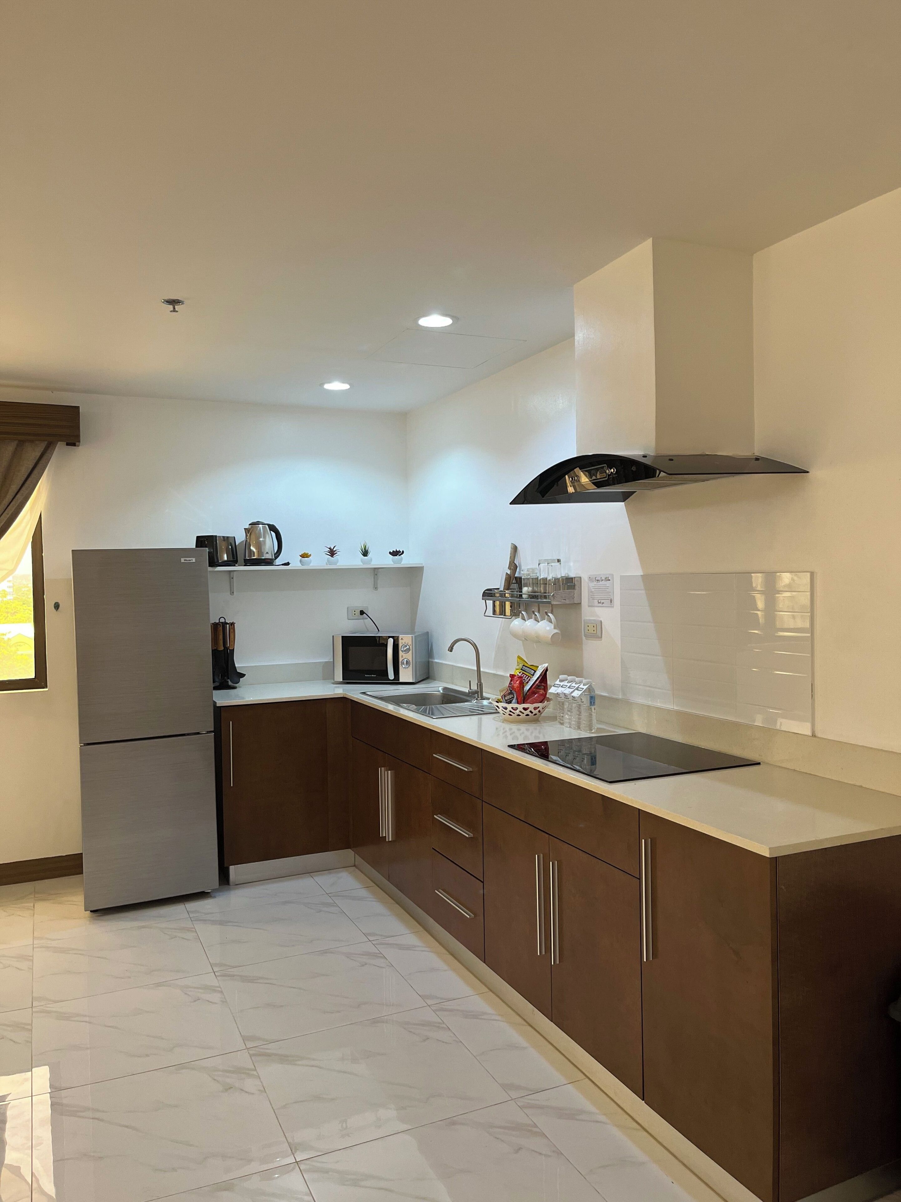A modern kitchen with a refrigerator, microwave, sink, and a range hood.