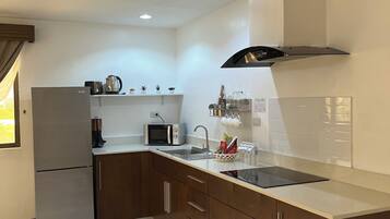 A modern kitchen with a refrigerator, microwave, sink, and a range hood.