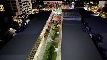 An aerial view of a rooftop area with a long, narrow pathway lined with trees and seating areas.