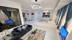 A modern living room with a sofa, a coffee table, and a TV. There is a staircase leading to another level. - 88th Avenue (Cebu City)