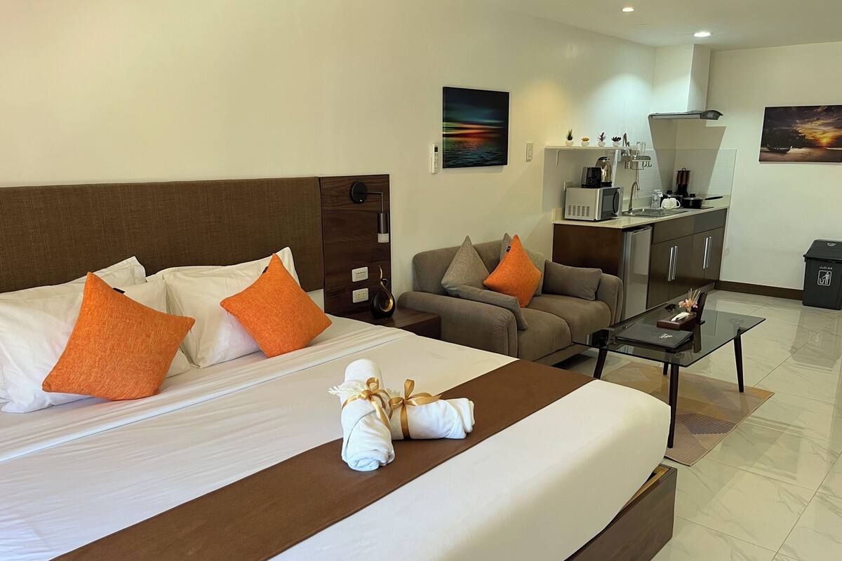 Een hotelkamer met een groot bed, twee banken, een salontafel en een kitchenette.