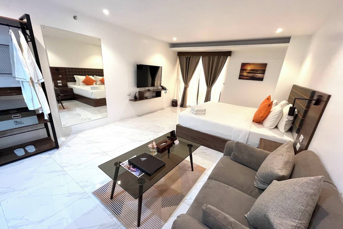Een moderne hotelkamer met een bed, bank, televisie en een klein tafeltje.