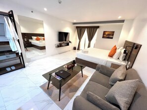 Een moderne hotelkamer met een bed, bank, televisie en een klein tafeltje.